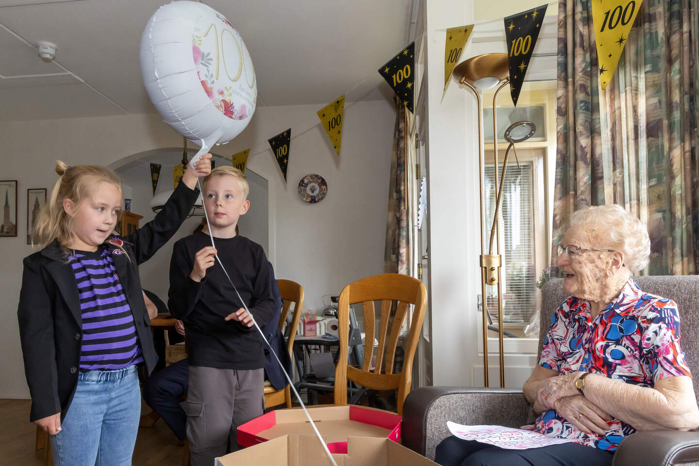 Achterkleinkinderen Cas en Nora komen met een ballon in een doos binnen. 